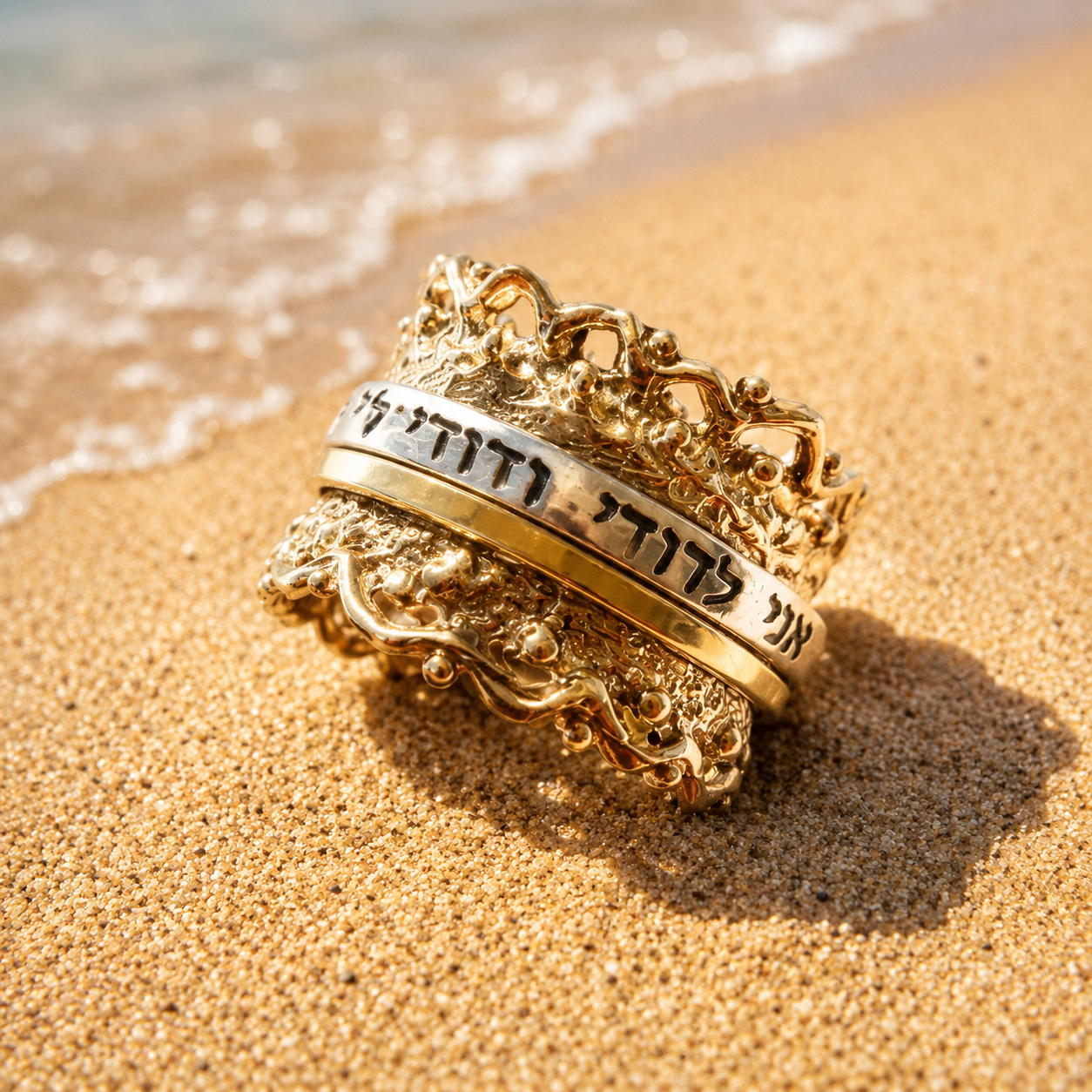 Women’s engraved spinner ring displayed on beach sand