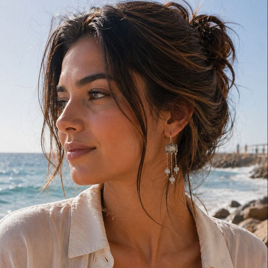 Woman with beach hair and earrings standing by the ocean